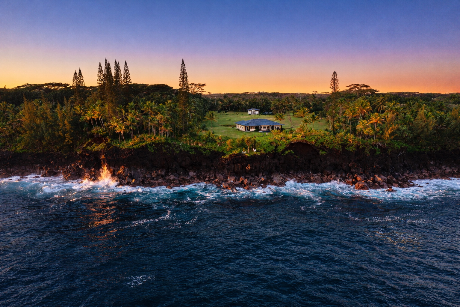 Straight-on drone view of the estate at dusk above the lava coast and deep blue ocean