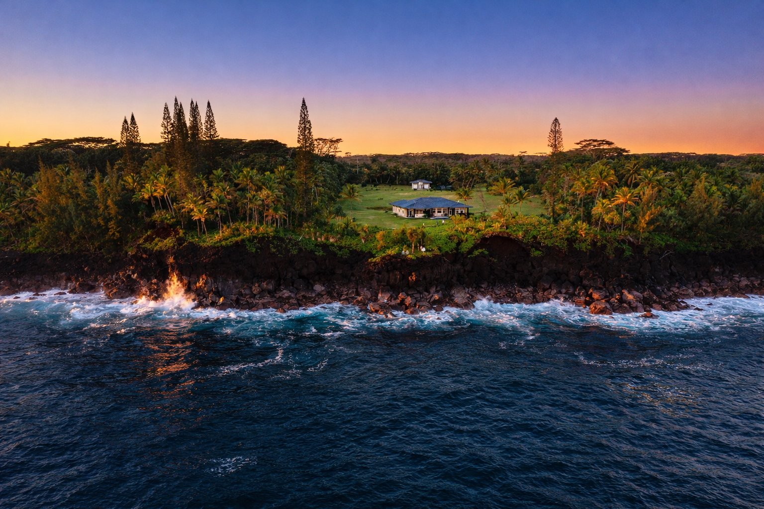 Straight-on drone view of the estate at dusk above the lava coast and deep blue ocean