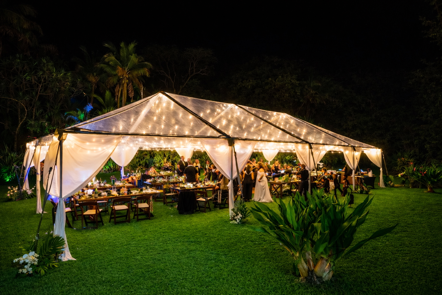 A reception tent glows on the lawn at Wild Blue Waters as evening settles over the Pacific.