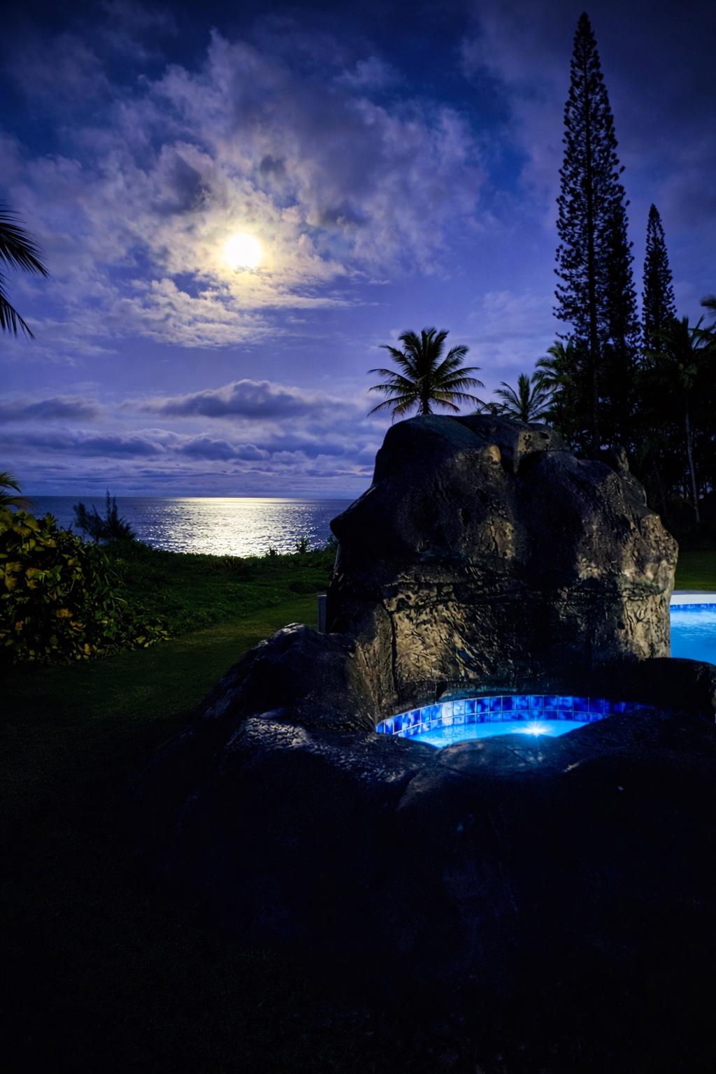 Moonlit oceanfront jacuzzi glowing blue under a full moon