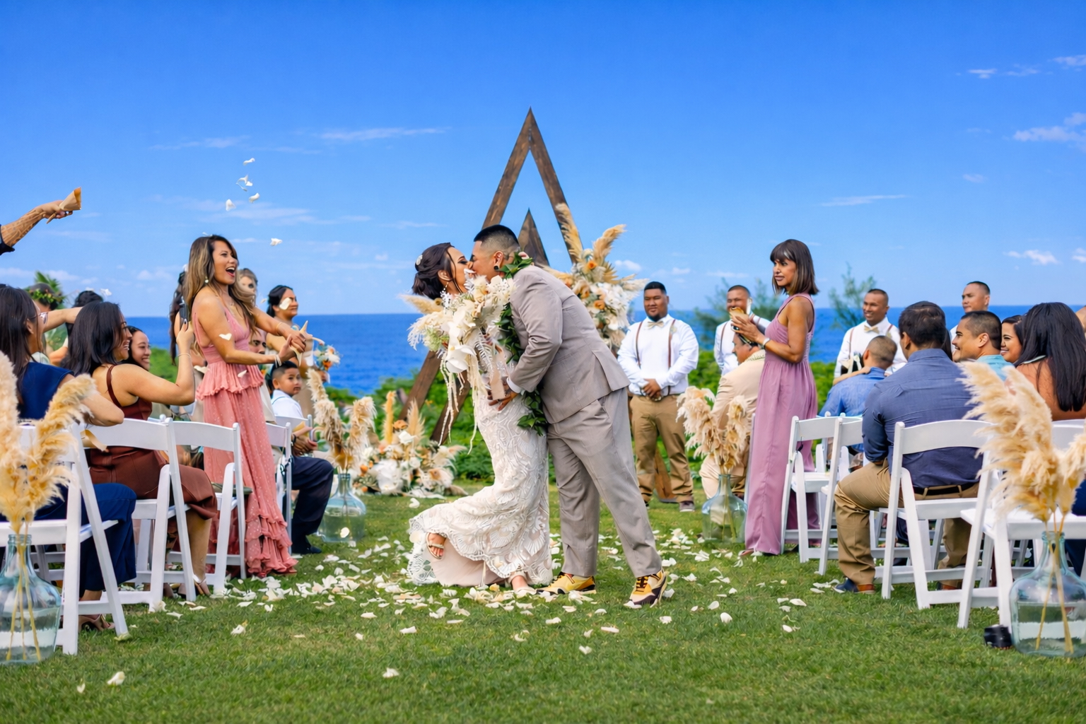 Bride and groom kissing at the ceremony altar with guests gathered beside the ocean